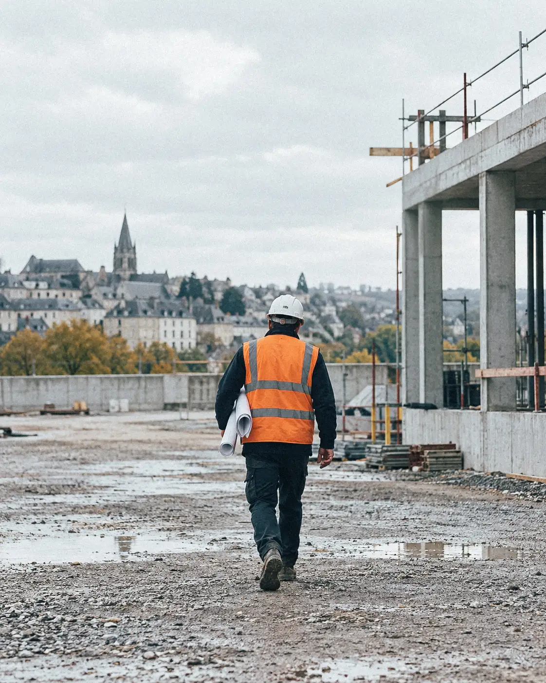 Conducteur de travaux traversant un chantier, plans sous le bras