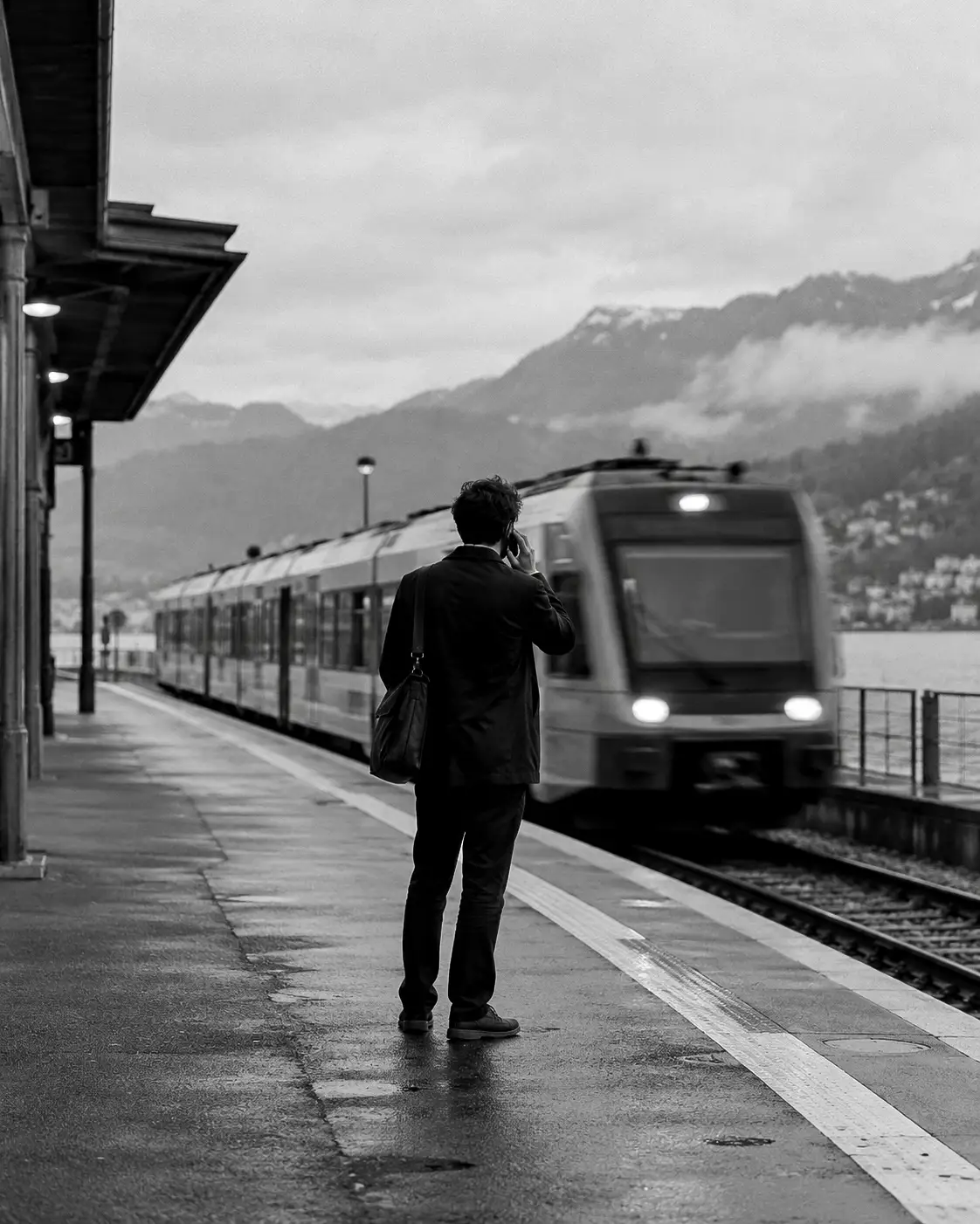 Commercial au téléphone sur un quai de gare, en noir et blanc